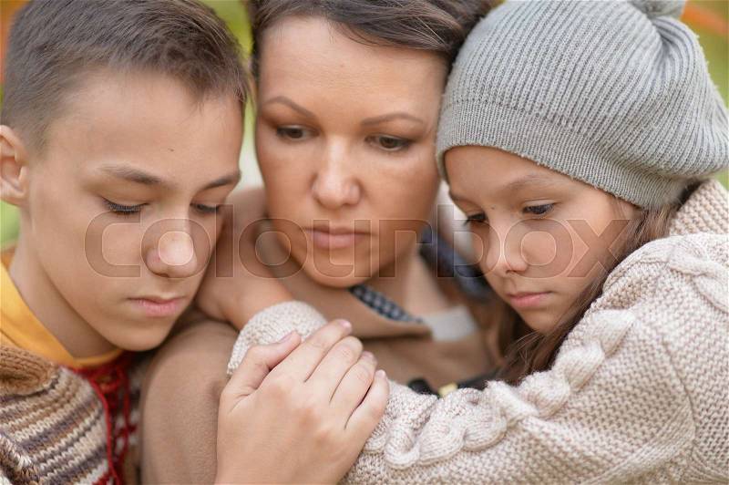 Portrait of sad mother and children in autumnal park, stock photo