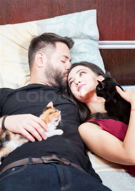 Inlove couple on the bed with their cats. Relax and love. Animal care. Animal lovers, stock photo