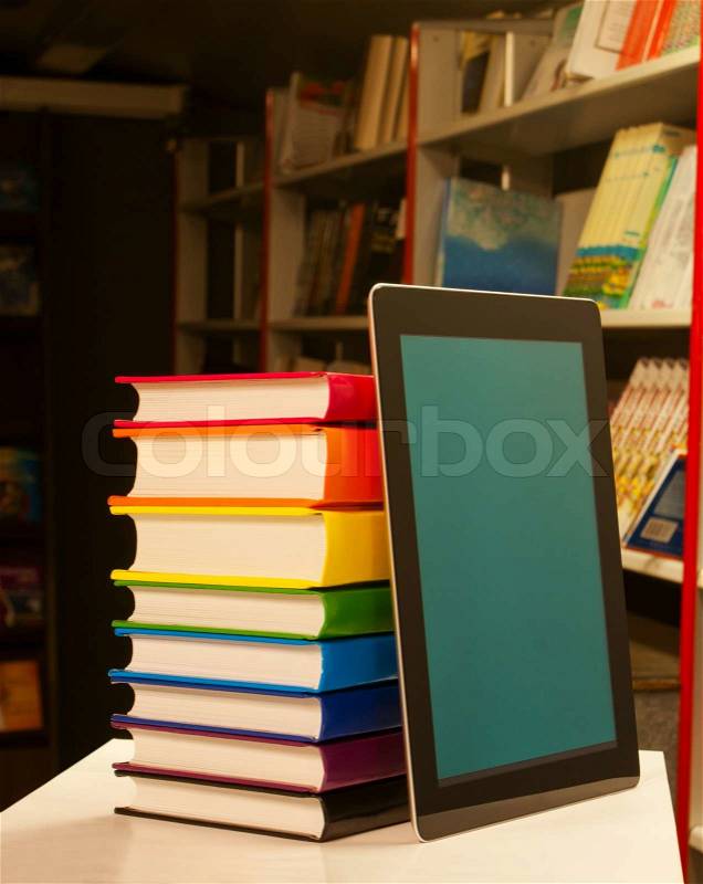 Stack of colorful books and electronic book reader in the book shop, stock photo