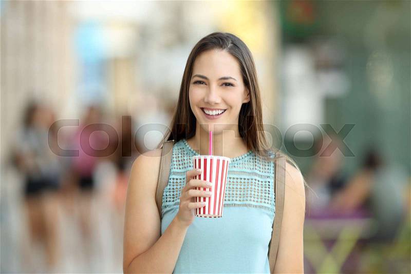 Front portrait of a girl holding a take away drink and looking at camera on the street, stock photo