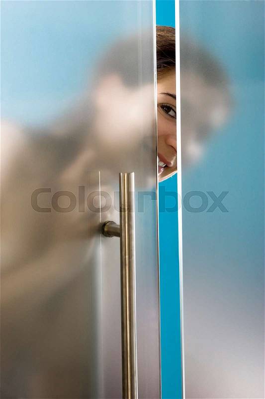 Beautiful and happy woman looking and closing the bathroom door, stock photo