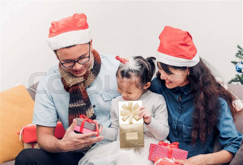 Happy family Asia family wear santa claus hat exchange Christmas gift box at house xmas party,Holiday celebrating festive concept,vintage filter, stock photo