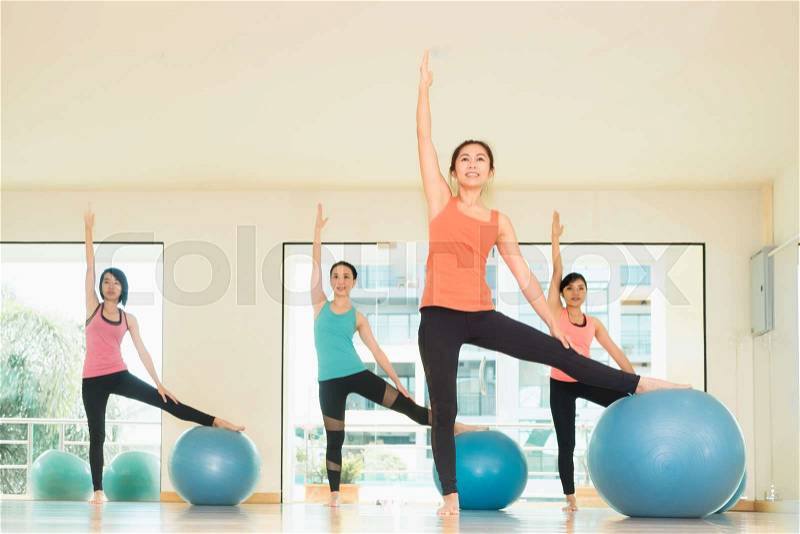 Yoga class in studio room,Group of people doing yoga pose with training ball, stretching pose,Wellness and Healthy Lifestyle, stock photo