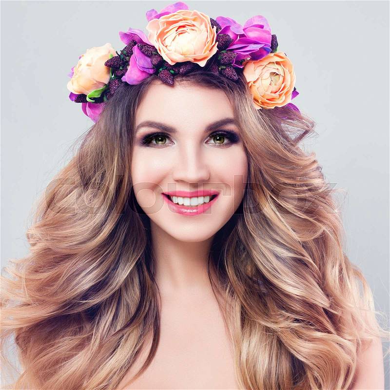 Blossom Beauty. Beautiful Woman Spa Model with Wavy Blonde Hair, Makeup and Colorful Flowers Wreath, Perfect Female Face Closeup, stock photo