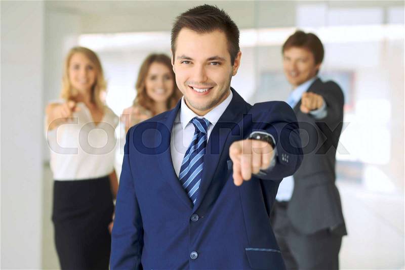 Happy smiling businessman and his colleagues pointing by finger into the camera. Concept of employer and success team, stock photo