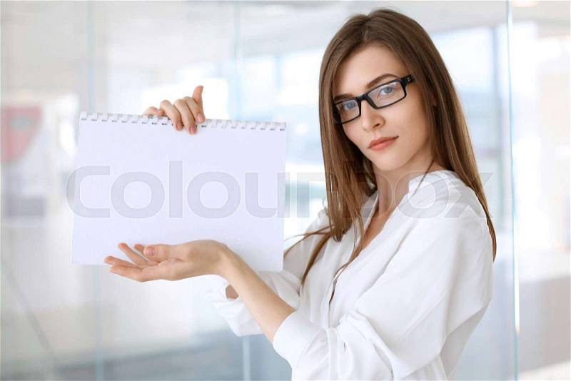 Business woman keeping copy space area while standing in the office, stock photo