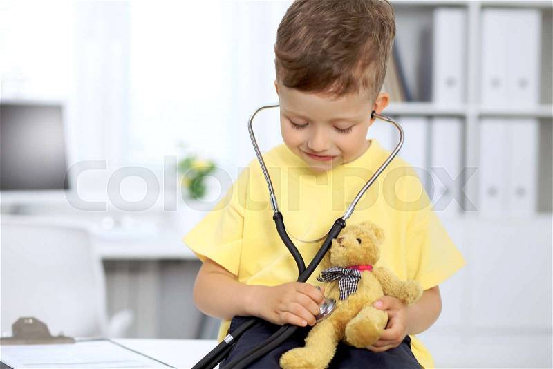 Happy little patient after health exam. Little doctor examining a toy bear with stethoscop, stock photo
