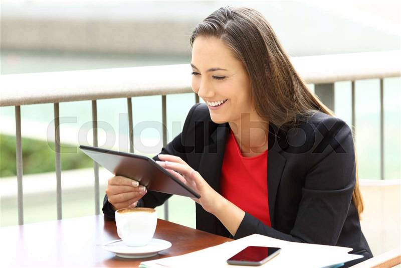Single executive working on line using a tablet sitting in a bar terrace, stock photo