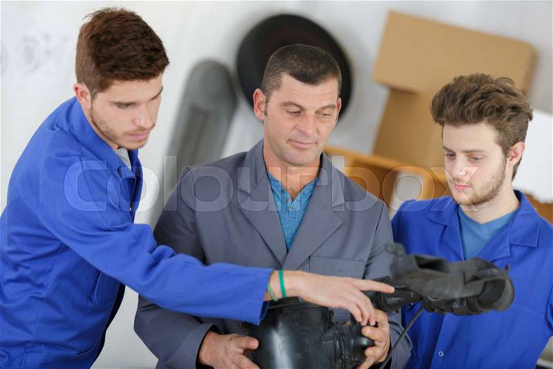 Teacher helping students training to be car mechanics, stock photo