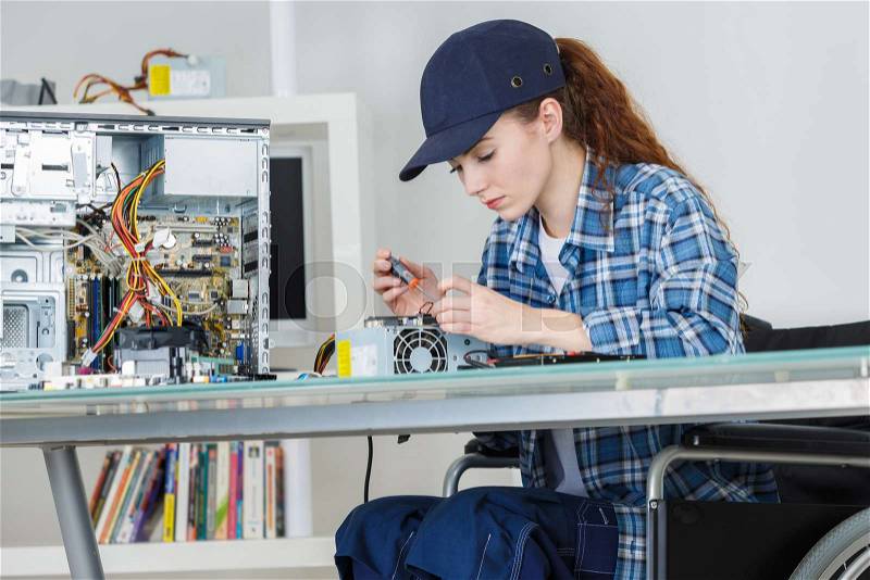 Young smiling brunette woman technician repairs a computer, stock photo