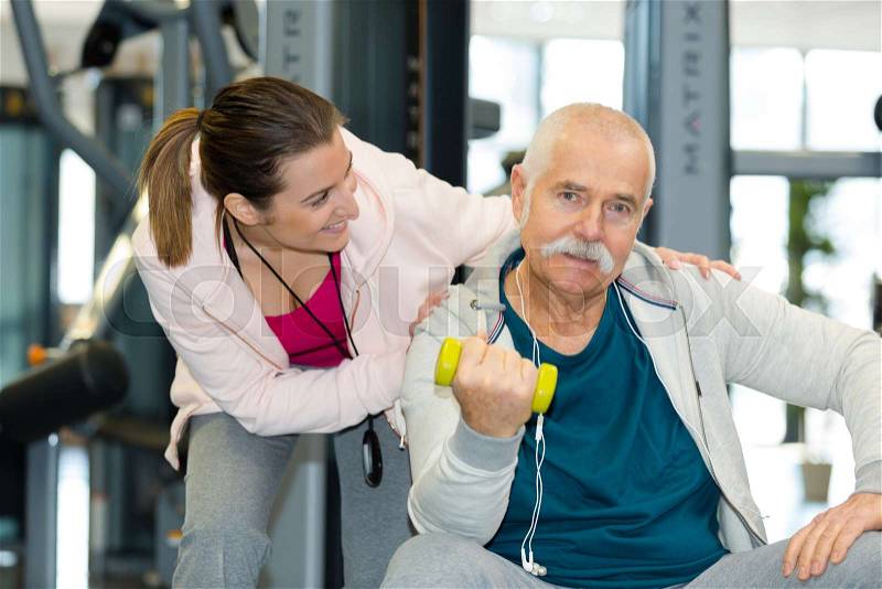 Happy senior working-out with weights and personal fitness trainer, stock photo