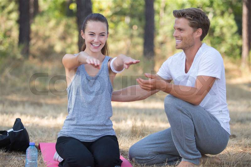 Young couple training yoga in the park, stock photo
