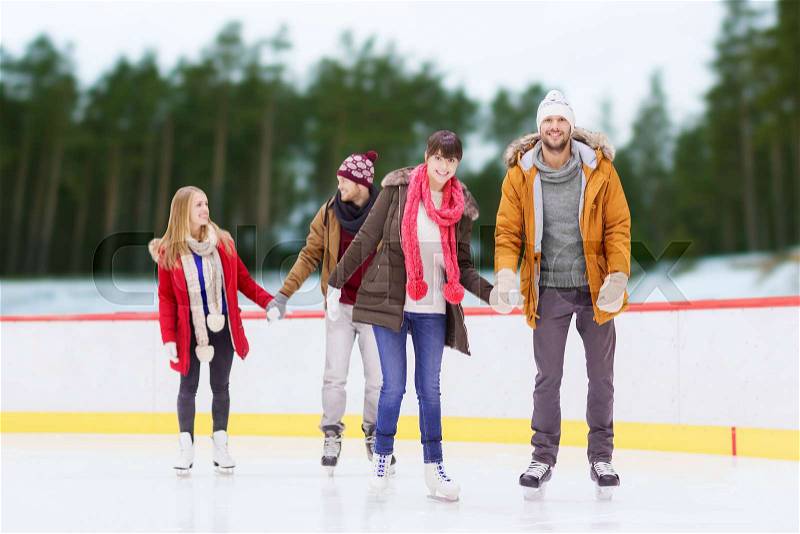 Friendship, sport and leisure concept - happy friends holding hands on skating rink over outdoor background, stock photo