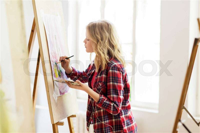 Art school, creativity and people concept - student girl or artist with easel, palette and paint brush painting still life picture at studio, stock photo