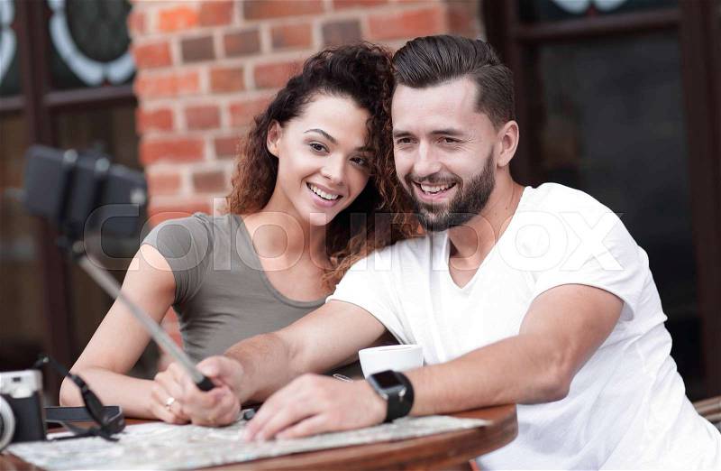 Happy cheerful couple sitting down at a cafe and making selfie, stock photo