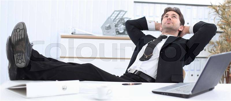 Businessman relaxes sitting behind abusinessman relaxes sitting behind a Desk in a private office Desk, stock photo