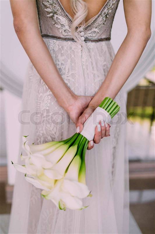 Beautiful wedding bouquet of calla flowers in hands of the bride. Artwork. Soft focus on a bouquet. Outdoor, stock photo