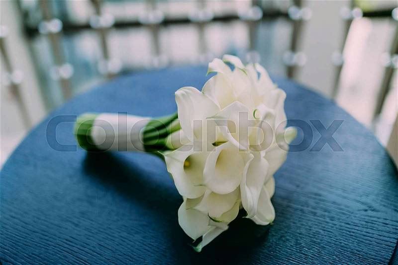 Beautiful wedding bouquet of calla flowers on blue table background. Artwork. Soft focus on a bouquet. Outdoor, stock photo