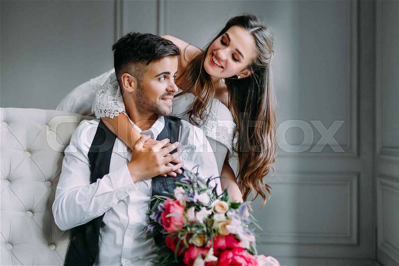 Cheerful bride hugging the groom. Newlyweds laughing and looking at each other . Artwork. Wedding. Close-up. Selective, soft focus on the girl, stock photo
