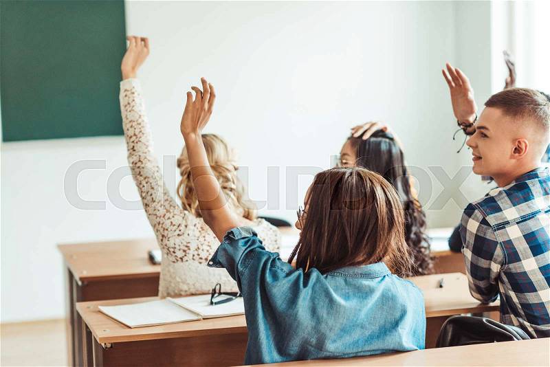 Group of students raising hands in class on lecture, stock photo