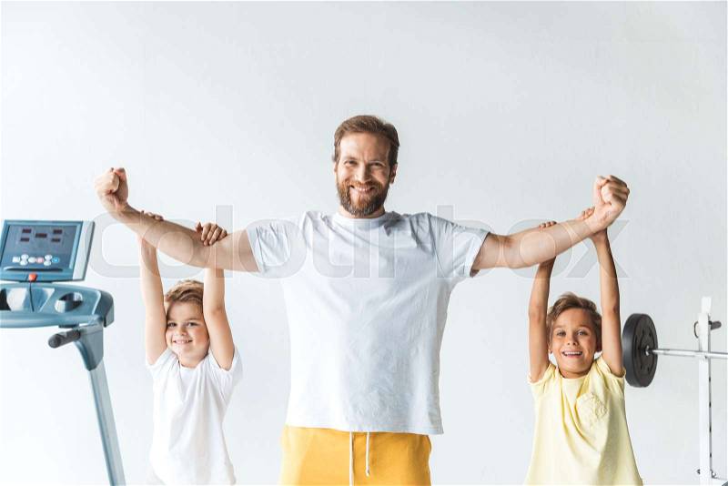 Happy sportive father and sons smiling at camera in gym , stock photo
