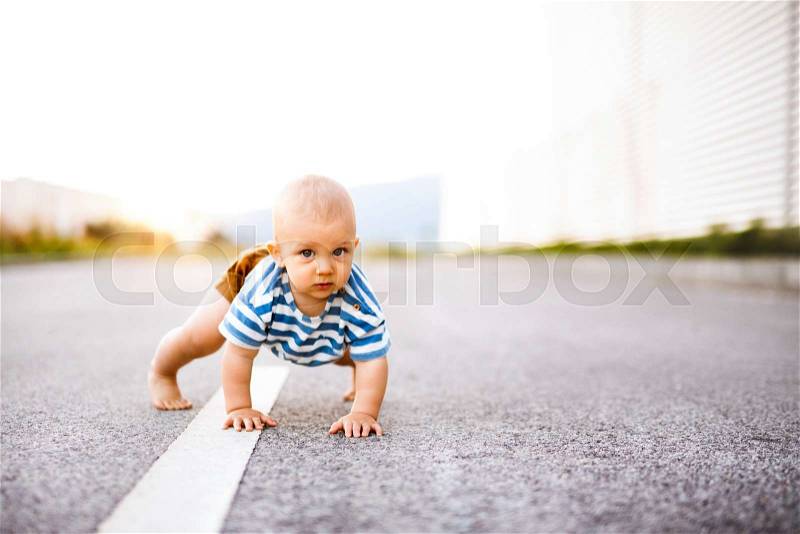 Cute little baby boy crawling outside on the road. Close up, stock photo