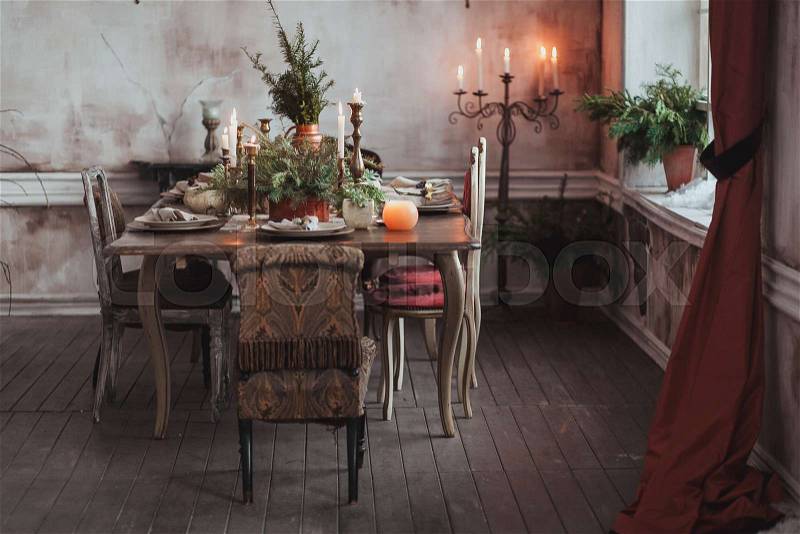 Christmas table setting. Vintage chairs, natural pine tree branches, candles. Rural or rustic style decorations, stock photo