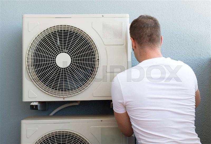 Male technician installing air-conditioning system, stock photo