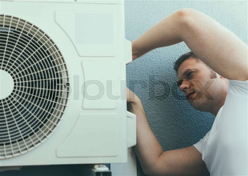 Male technician installing air-conditioning system, stock photo