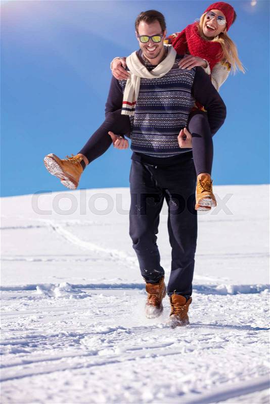 Loving couple playing together in snow outdoor. Winter holidays in mountains. Man and woman wearing knitted clothing having fun on weekends, stock photo