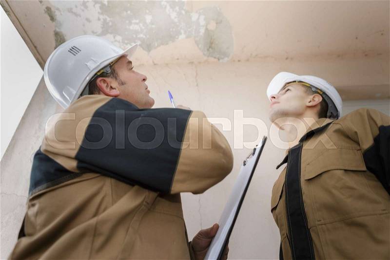 Plumber looking at a ceiling leak, stock photo
