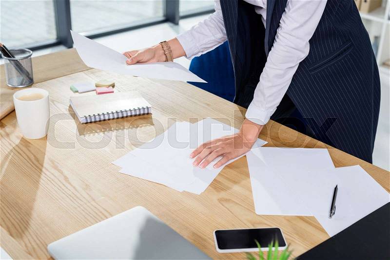 Cropped shot of businesswoman in office standing over desk with some paperwork, stock photo