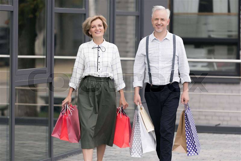 Husband and wife walking with paper bags from shopping, stock photo