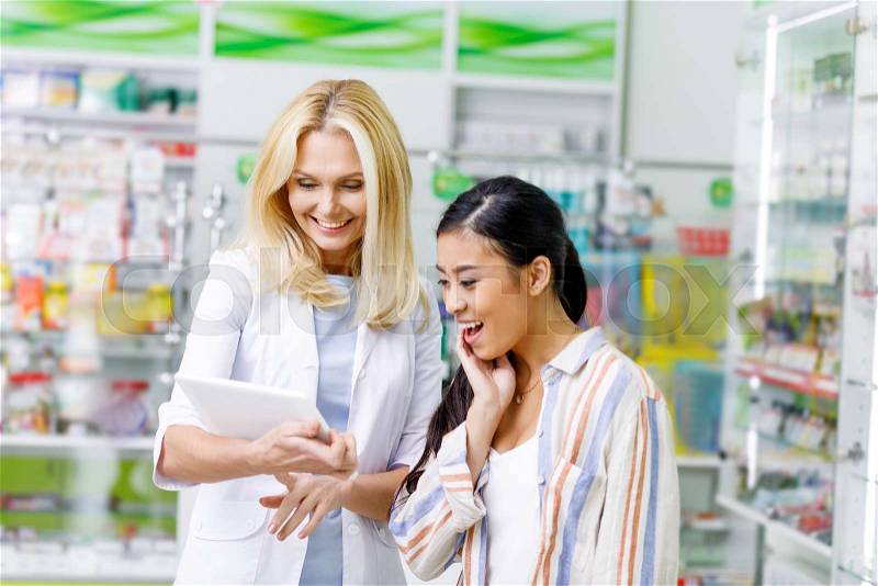 Smiling pharmacist and customer using digital tablet in drugstore , stock photo