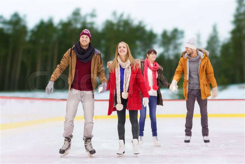 Friendship, sport and leisure concept - happy friends holding hands on skating rink over outdoor background, stock photo