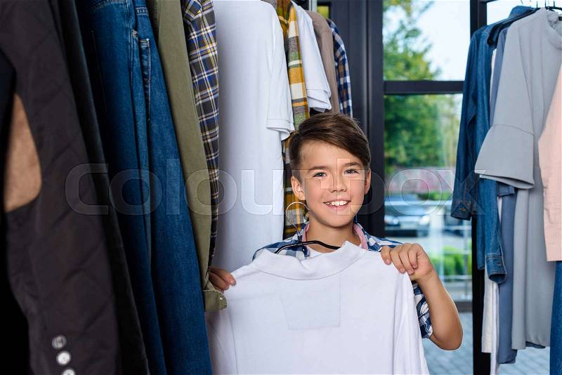 Adorable smiling boy with clothes in boutique , stock photo