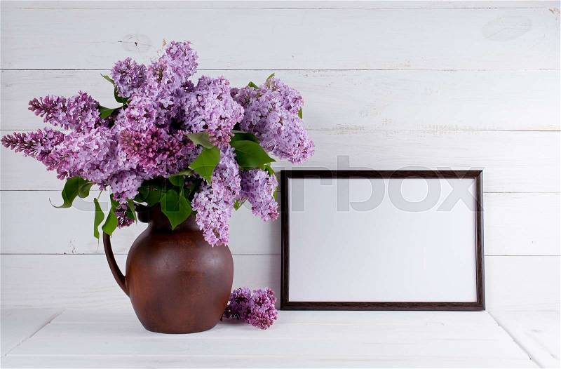 Lilac Bouquet in clay jug with motivational frame with place for your text or picture on background of white wooden planks in scandinavian style, stock photo