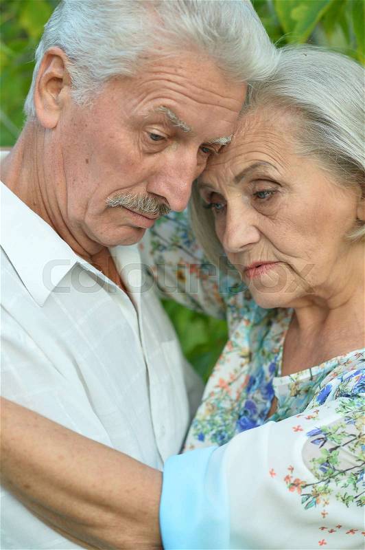 Sad senior couple in a summer park, stock photo