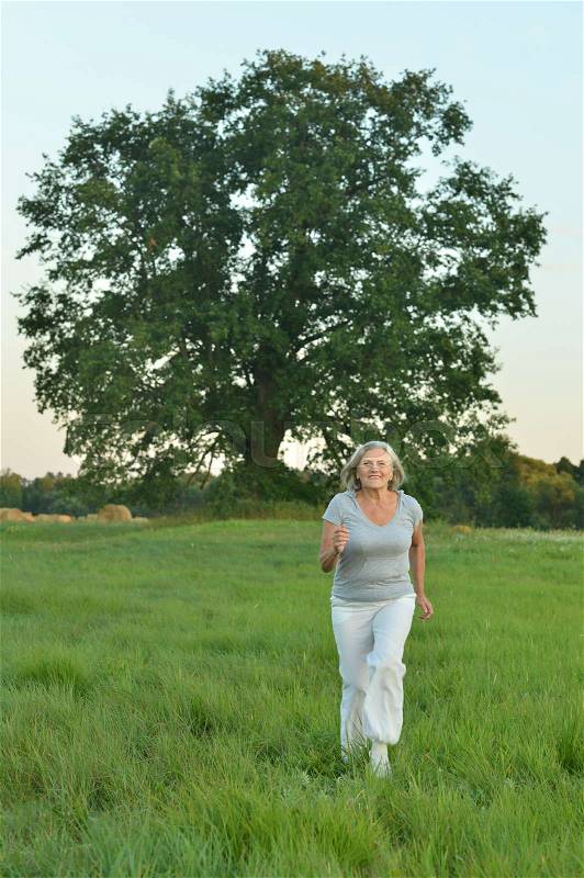 Portrait of beautiful caucasian senior woman running in field, stock photo