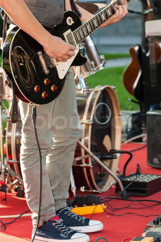 Guitarist sets up an electric guitar before the concert begins on the street, stock photo