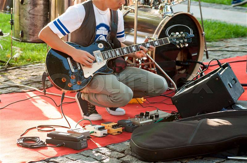 Guitarist sets up an electric guitar before the concert begins on the street, stock photo