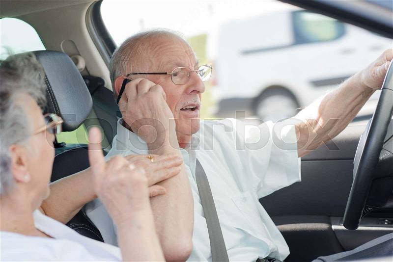 Senior woman protesting against her husband driving and calling, stock photo