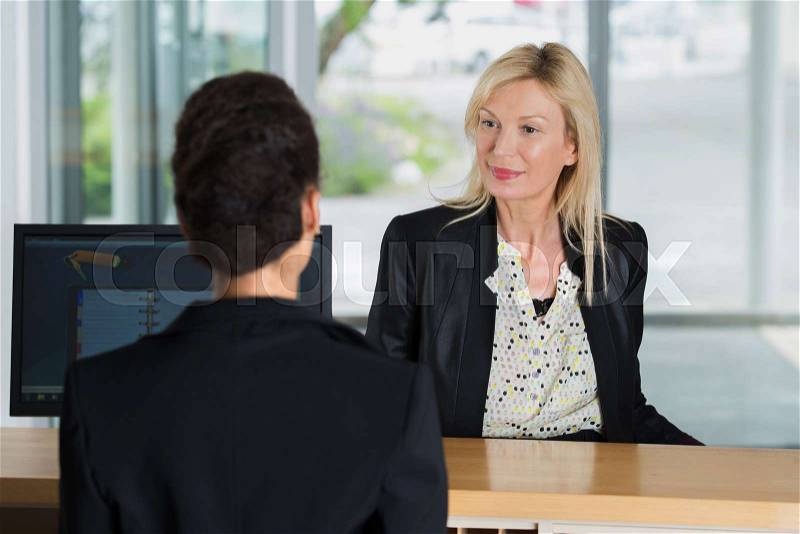 Beautiful woman at the reception of a hotel checking in, stock photo