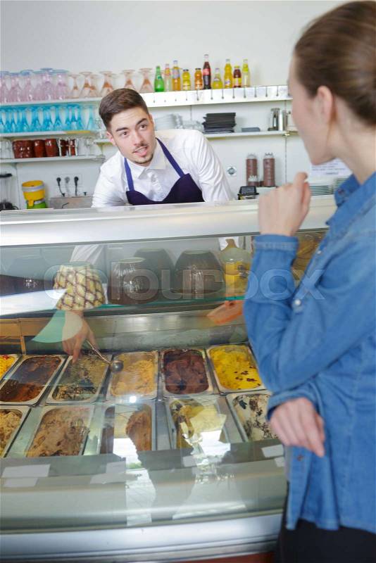 Man sells ice cream in ice cream store, stock photo