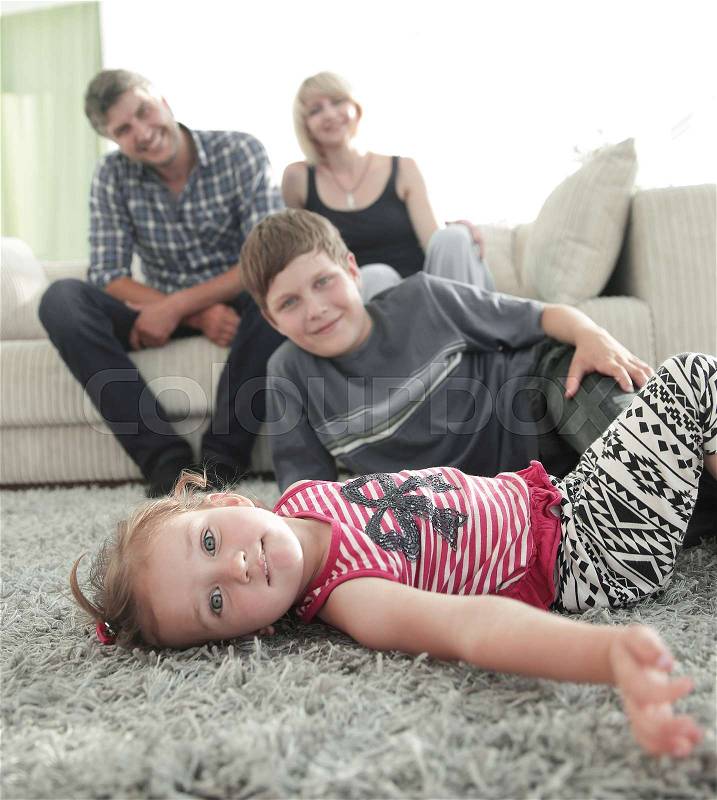 Portrait of children resting on carpet while parents sitting in background at home, stock photo