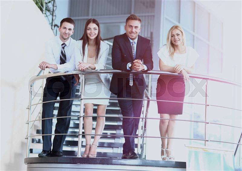 Portrait of positive business group standing on stairs of modern office, stock photo