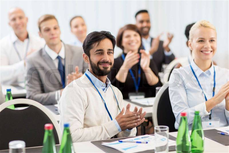 Business and education concept - group of happy people applauding at international conference, stock photo