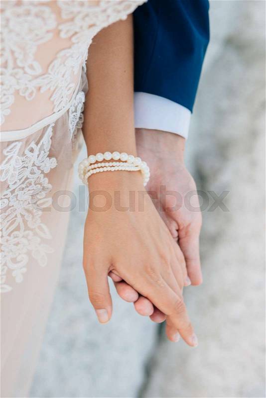 The groom gently holds the bride by the hand, close-up, stock photo