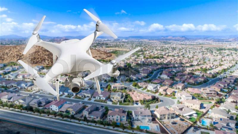 Unmanned Aircraft System (UAV) Quadcopter Drone In The Air Over Residential Neighborhood, stock photo