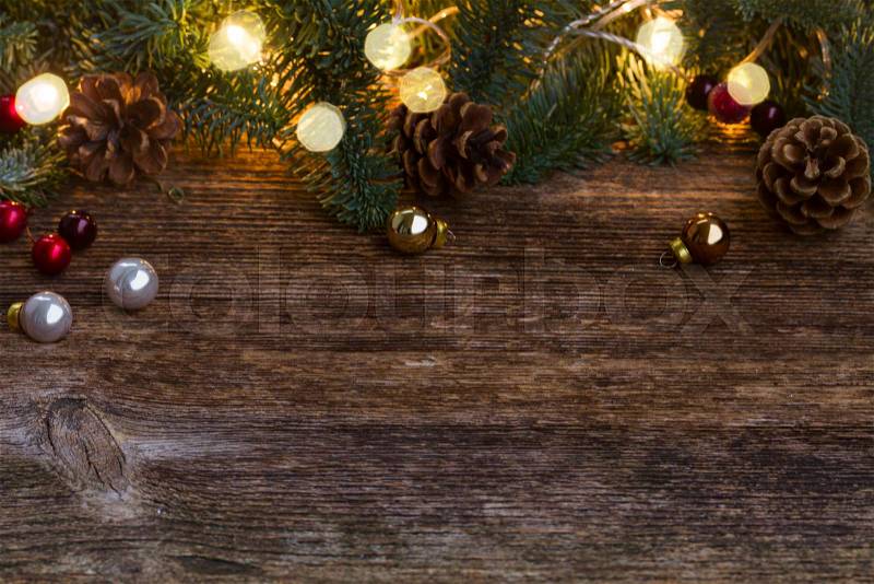 Christmas border with evergreen fir tree twigs and lights on old wooden background, stock photo